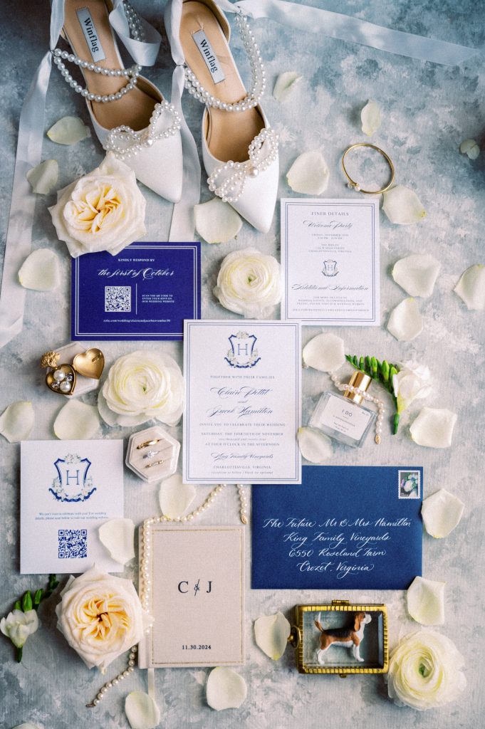 Flat lay of wedding invitation cards, pearl jewelry, and rings styled with soft fall tones for Claire and Jake’s vineyard wedding.