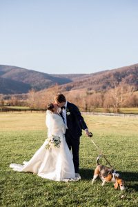 The couple sharing a tender kiss with the scenic vineyard view behind them.