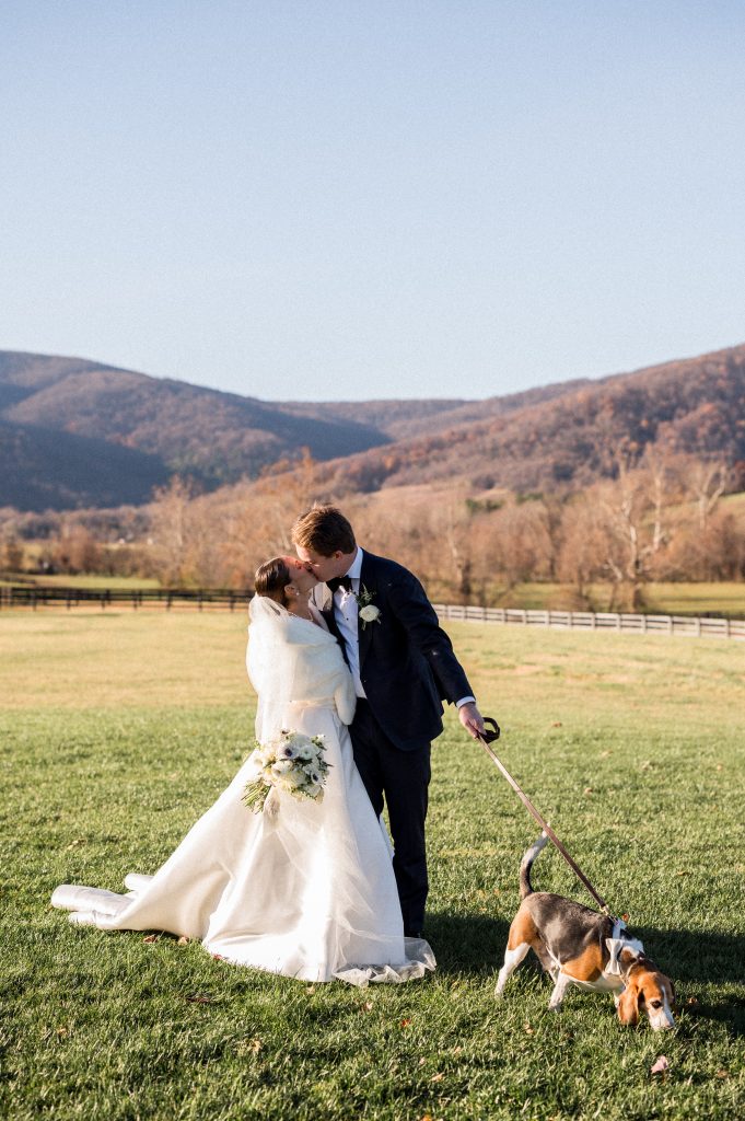 The couple sharing a tender kiss with the scenic vineyard view behind them.