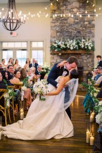 Groom leaning in to kiss his bride during the ceremony as she’s gracefully dipped back, creating a timeless and romantic vineyard moment at King Family Vineyards.