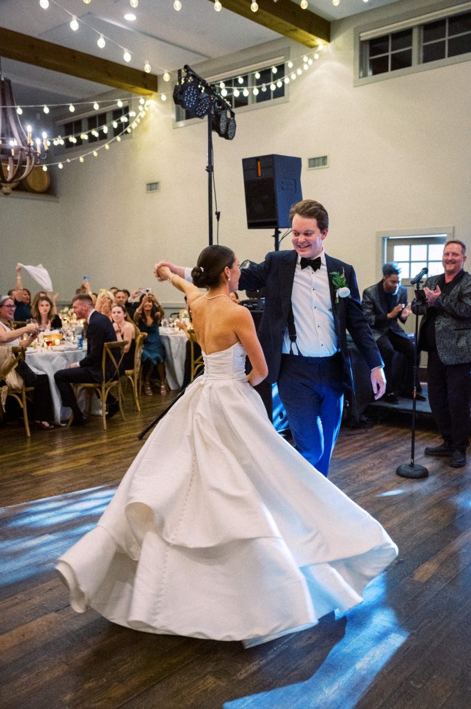 Claire and Jake sharing their first dance under string lights during the vineyard reception.